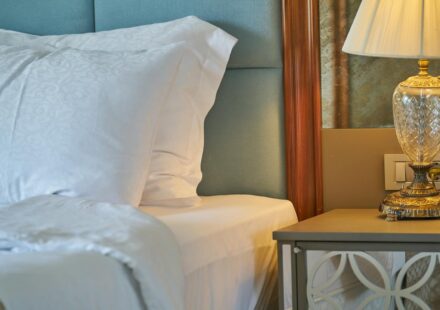 Elegant close-up of a comfortable bedroom setup with white linens and a decorative lamp.