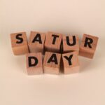 Wooden blocks arranged to spell Saturday on a beige surface. Perfect for weekend themes.