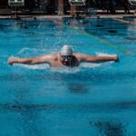 A swimmer performs the butterfly stroke in an outdoor pool, showcasing athleticism and competition in Aguascalientes, Mexico.
