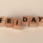 Wooden letter blocks spelling out 'Friday' on a neutral beige background.