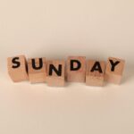 Wooden letter blocks spelling 'Sunday' on a neutral background for weekend concepts.