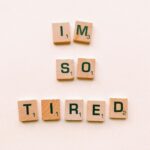 Close-up of Scrabble tiles spelling 'I'm So Tired' on a plain surface, capturing a conceptual theme.