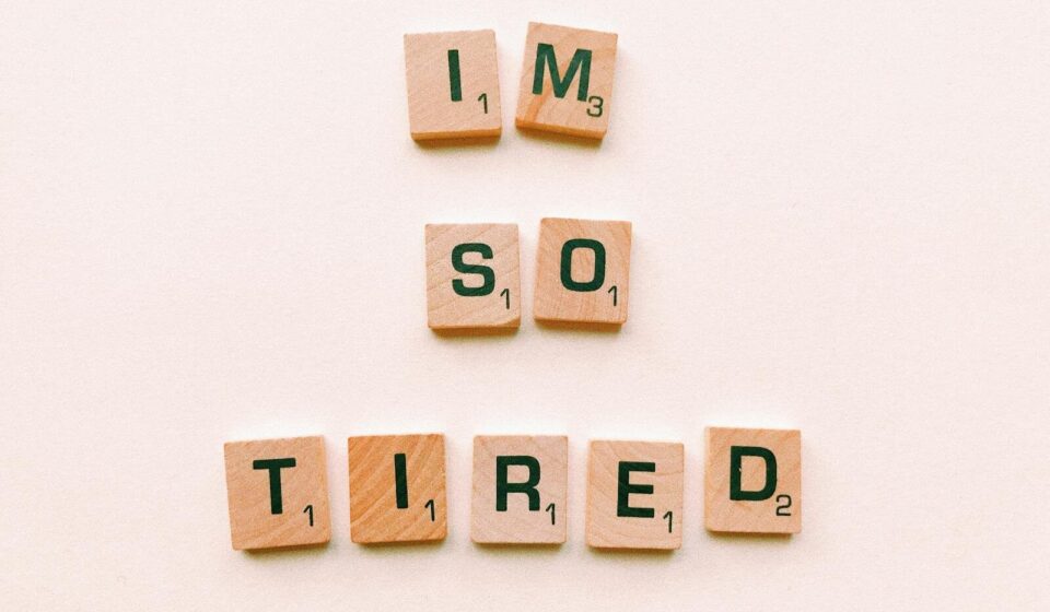 Close-up of Scrabble tiles spelling 'I'm So Tired' on a plain surface, capturing a conceptual theme.