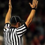Referee raising hands to signal a goal or touchdown in a match.