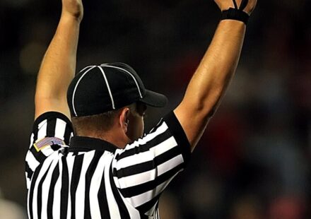 Referee raising hands to signal a goal or touchdown in a match.