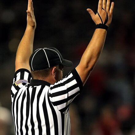 Referee raising hands to signal a goal or touchdown in a match.