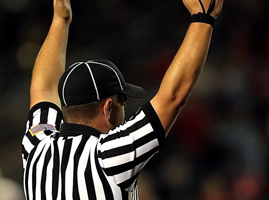 Referee raising hands to signal a goal or touchdown in a match.