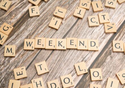 Wooden Scrabble tiles spelling 'weekend' on a rustic wooden table.