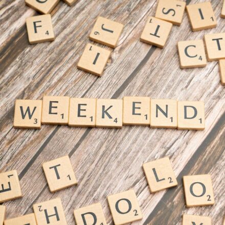 Wooden Scrabble tiles spelling 'weekend' on a rustic wooden table.