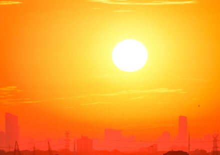 A city skyline silhouetted against a vivid, orange sunset sky.