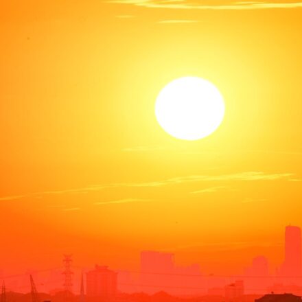 A city skyline silhouetted against a vivid, orange sunset sky.