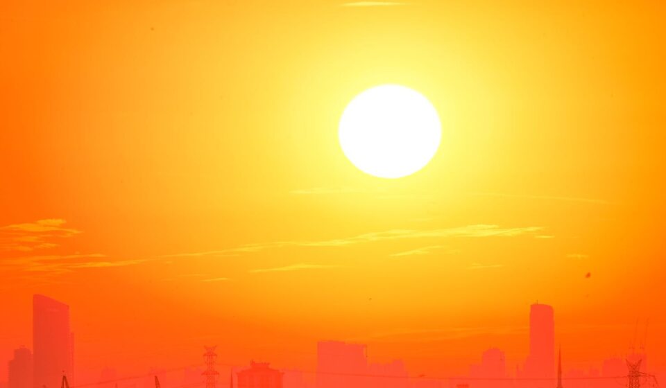 A city skyline silhouetted against a vivid, orange sunset sky.