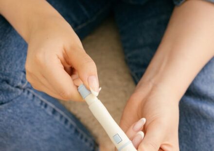 A close-up of a person holding a lancet pen, preparing for a blood glucose test, highlighting diabetes management.
