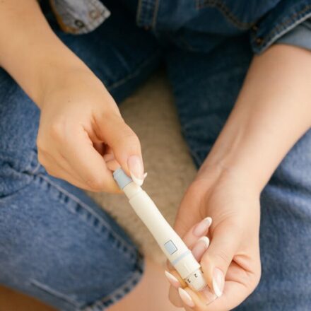 A close-up of a person holding a lancet pen, preparing for a blood glucose test, highlighting diabetes management.