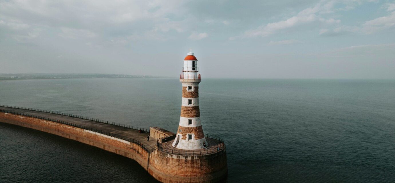 an aerial view of a lighthouse in the middle of the ocean