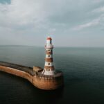 an aerial view of a lighthouse in the middle of the ocean