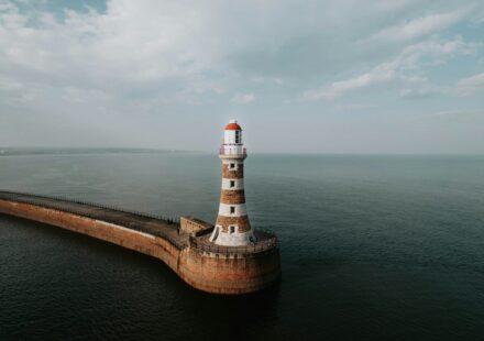 an aerial view of a lighthouse in the middle of the ocean