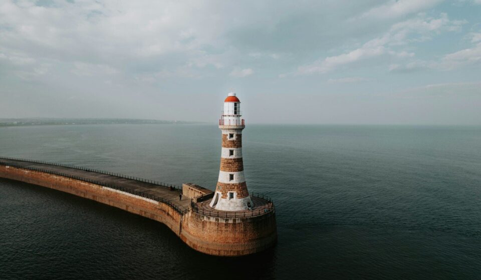 an aerial view of a lighthouse in the middle of the ocean